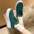 Side view of dark green suede platform sneakers paired with white ribbed socks on a sofa - 36 / Teal