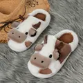 Detail view of cozy cow-themed plush slippers displayed on a soft grey textured rug. - 36-37 / Brown White