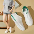 Detailed view of white casual sneakers with green accents in a lifestyle setting. - 35 / Green