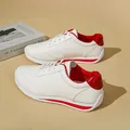 Close-up of white women's casual sneakers with stylish red heel and stripe details. - 35 / Red