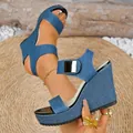Close-up detail of blue denim wedge sandal featuring ankle strap with square gold buckle. - 35 / Denim Blue