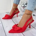 Detail view of stylish red high heel sandals with an elegant decorative bow on the toe. - 35 / Red