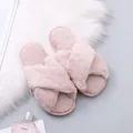 Close-up of pink fuzzy cross-strap slippers with soft plush texture on white fur rug. - 36 / Pink