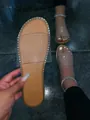 Detailed view of women's flat slide sandals featuring clear strap and rhinestone trim - Clear