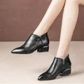 Detailed macro view of women's black leather ankle boots with side zip and bow detail - 35 / Black