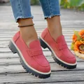Elegant pink suede loafers featuring chunky black platform soles on a wooden deck - Red