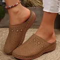 Detailed view of women's brown closed-toe platform slides with perforated floral patterns - Brown