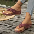 Detail van bordeauxrode sleehak-teenslippers met leren bloemen op een houten dek. - Bordeauxrood