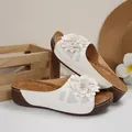 Gros plan de sandales compensées blanches avec décor floral et détails découpés. - 36 / Blanc