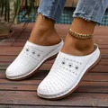 Close-up of white perforated platform mules with decorative studs on wooden deck - 36 / White