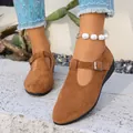 Détail de chaussures plates en daim marron à bride en T avec boucle et petit talon compensé - Marron
