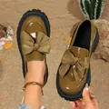 Detail view of olive green patent leather loafers with large bows and platform soles. - 36 / Brown