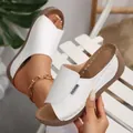 Detail view of white peep-toe wedge sandals featuring a platform sole and stitch accents. - 36 / White