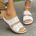 Detailed view of white wedge sandals with laser-cut floral patterns on feet - 36 / White