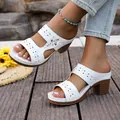 Close-up of stylish white laser-cut block heel slide sandals on a rustic wooden deck - 36 / White