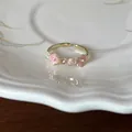 Detail van elegante goudkleurige open ring met roze emaille bloemen en kristallen. - Roze Bloem Ring