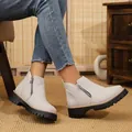 Close-up view of light grey suede ankle boots with side zipper and thick black lug sole - Off White