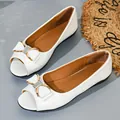 Elegant white flat open-toe shoes featuring a decorative bow with rhinestone accents - 35 / White