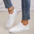 Close-up detail of women's minimalist white lace-up sneakers with flat rubber sole - 35 / White