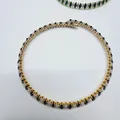 Close-up of elegant gold-plated necklace featuring black and clear oval zircons - White + Black