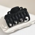 Classic matte black medium hair claw clip on a minimalist white stone background - Square Cat Eye Style / Black