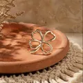 Close-up detail of a minimalist gold hollow heart four-leaf clover brooch on terracotta - Hollow Clover Style (XZ0039)