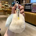 Close-up of a soft, fluffy off-white plush keychain with a cute tag held in hand. - White Pear No Pressure