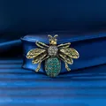 Vintage gold-tone bee brooch with green rhinestones shown on elegant blue satin. - Antique Gold Peacock Green Bee (XD824005-3) / Antique Gold, Green