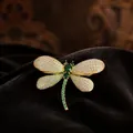 Detailed macro view of an elegant golden dragonfly brooch featuring green and white crystals - Dragonfly Style (XZ0175)