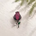Close-up van een elegante vintage rozenknopbroche met rode kristallen op een linnen doek - Roos/Camellia Broche