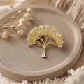 Close-up van de gouden wensboom broche met glinsterende gele kristallen details. - Gouden Wensboom Broche