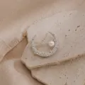 Dettaglio di una spilla a mezzaluna scintillante con una perla bianca su pietra naturale. - Argento