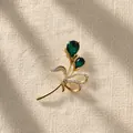 Detail van een elegante gouden tulpenbroche met groene edelstenen en kristallen. - Gouden Bloem Brosche
