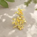 Gedetailleerde macro-opname van een elegante gouden osmanthus broche op getextureerd linnen. - Osmanthusboom Broche