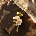 Gedetailleerd overzicht van een jasmijn broche met parelachtige blaadjes op hout - Jasmijnbloem Broche