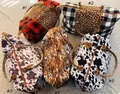 Close-up of assorted canvas weekender bags in leopard, cow, and plaid patterns. - Black and White Fuzzy Leopard Print / 22 Inch