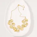 Detailed view of the gold-toned zinc alloy leaf pendant necklace on white tray - Leaf Necklace / Gold
