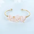 Detail showing raw rose quartz stones wrapped in gold wire on a cuff bracelet. - Rose Quartz