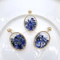 Detail view of three oval gold-framed pendants filled with blue crushed natural stones - Lapis Lazuli