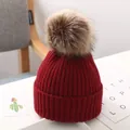 Detail eines weinroten Kinder-Strickhuts mit einer großen flauschigen Bommel - Burgunderrot