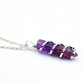 Nahaufnahme eines Amethyst-Sechseck-Anhängers mit silberner Drahtwicklung an einer feinen Kette. - Amethyst