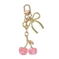 Close-up detail of a pink resin cherry keychain featuring a gold bow and clasp - Pink Glitter