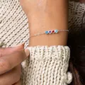 Detail view of a dainty silver birthstone bracelet with four colorful round zircons - Silver