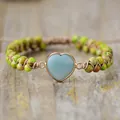 Detailed close-up of handmade woven heart-shaped imperial stone bracelet on wood - Yellow Green Imperial Heart