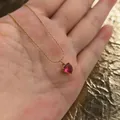 Detailopname van een hartvormige roze zirkoon hanger aan een goudkleurige ketting - Rood