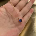 Detailopname van een blauwe hartvormige zirkoon hanger aan een gouden ketting - Blauw