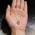 Detailopname van een vintage gouden ketting met een roze hartvormige zirkonia hanger - Roze