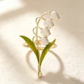 Close-up detail of lily of the valley napkin ring with white petals and green leaves - White