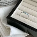 Makroansicht eines unregelmäßigen gewellten Silberrings mit hellblauem Emaille in einer Box. - Blau Emaille Wellen-Stil / Silber-Blau
