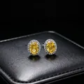 Macro detail of yellow oval moissanite stud earrings with diamond halo on black box. - Earrings (T16) / Yellow
